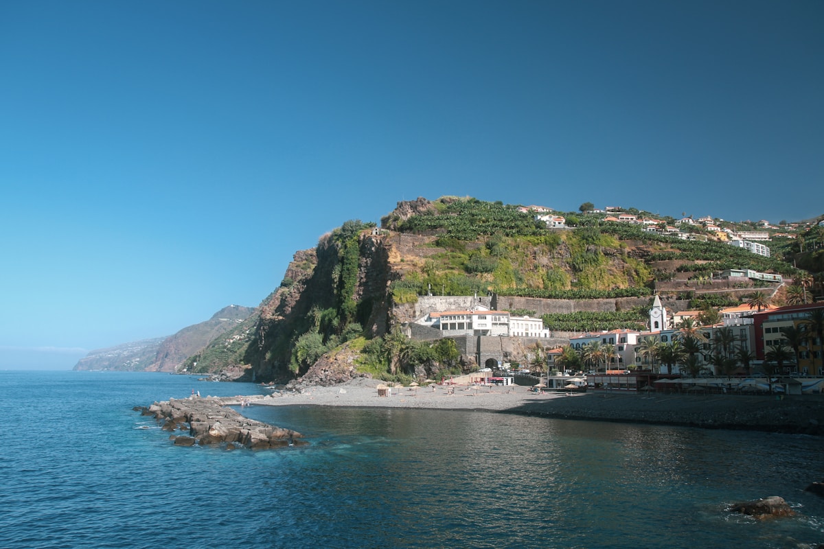 Coastal village on Madeira&rsquo;s steep volcanic hillside, with terraced slopes rising from the Atlantic. Photo by Lea Poisson on Unsplash