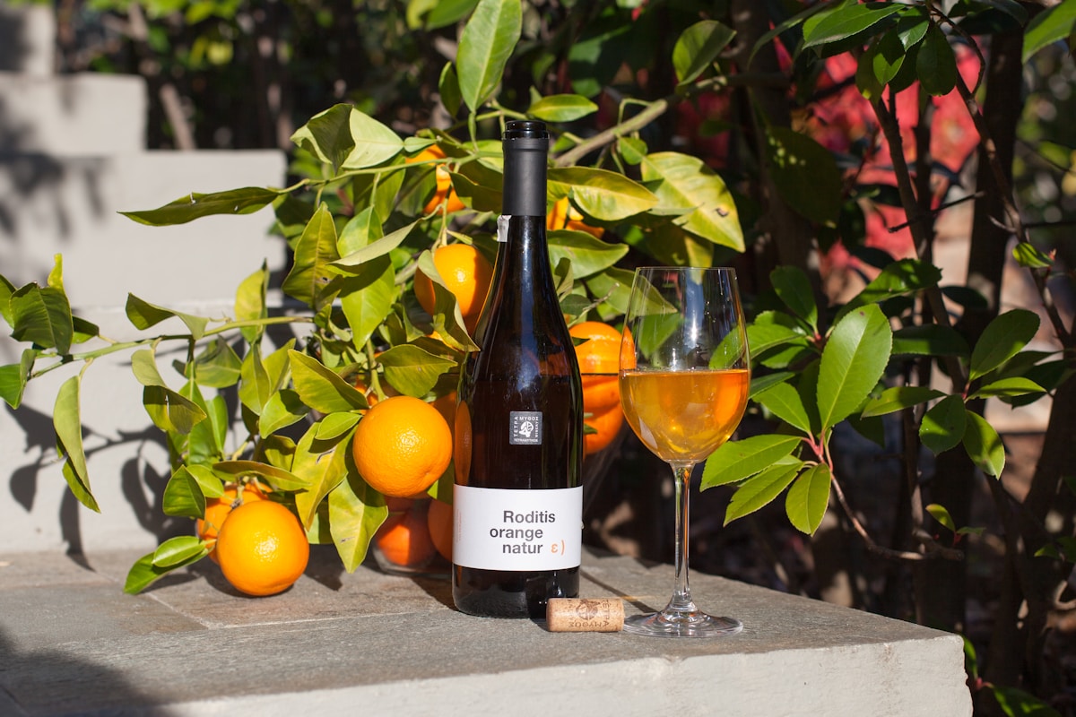 A bottle of natural orange wine with a glass of amber-hued skin-contact white wine. Photo by Alexandra Torro on Unsplash